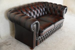 Tijdloze 2-zits Chesterfield met zacht geveerde vloerkleed en elegant design.
